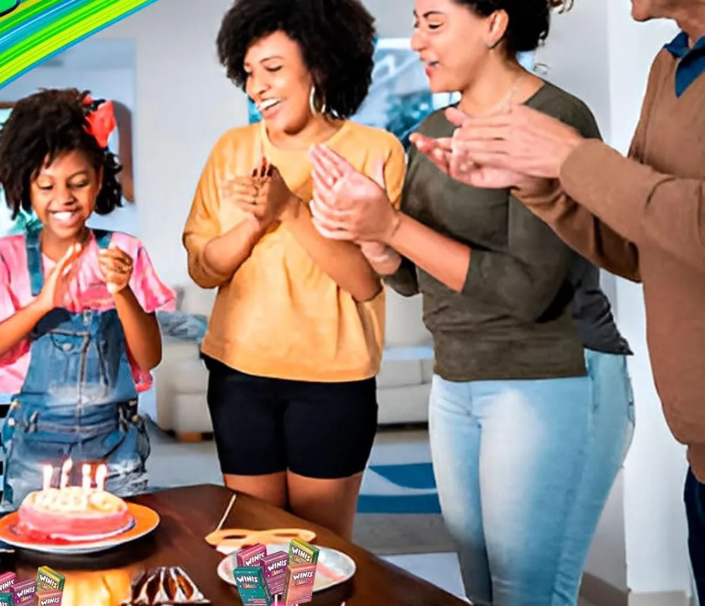 A family clapping around a birthday cake with Winis candy on the party table