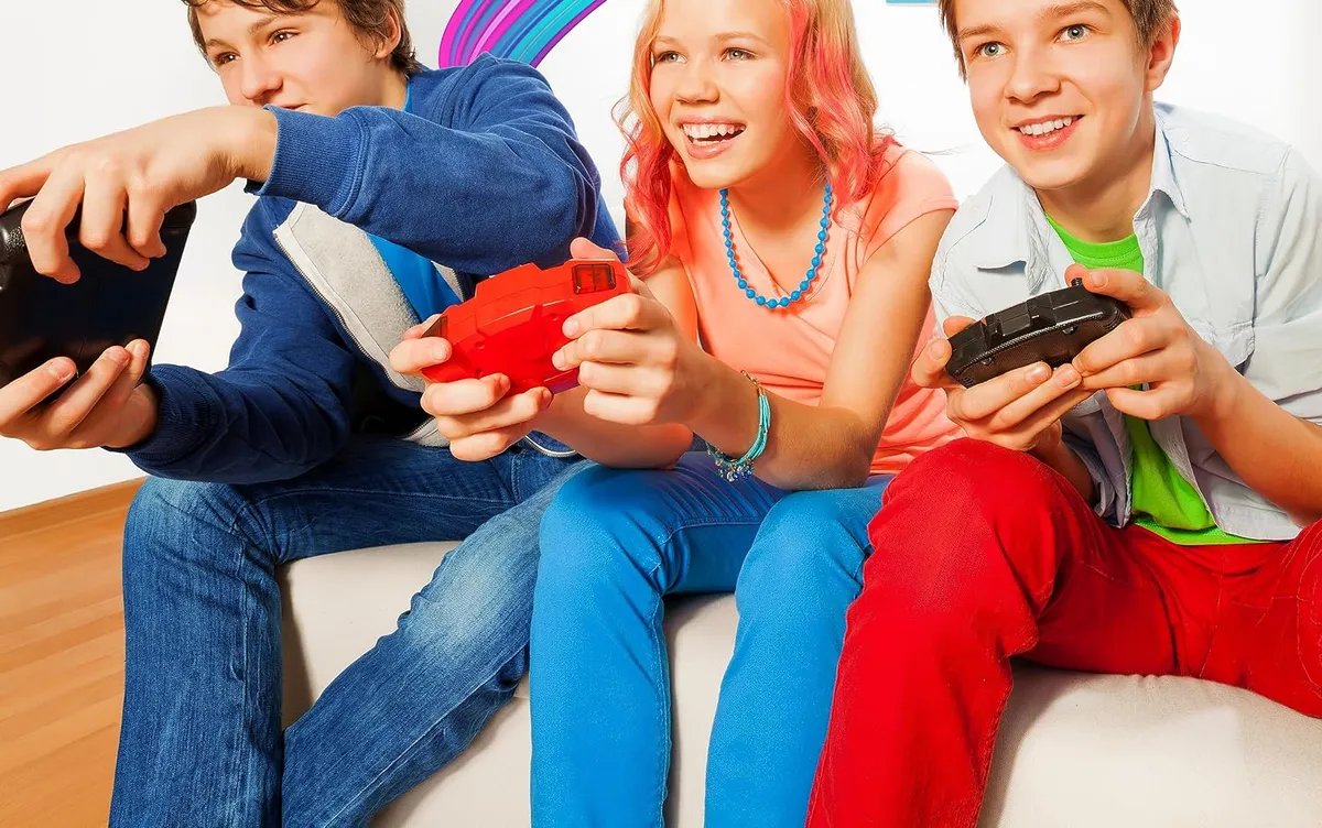 Three friends on a couch with game controllers, laughing at the screen